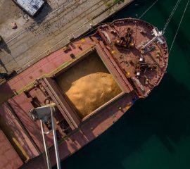 cargo ship or bulk carrier loaded to the brim with grain is preparing for departure, working sailors on deck are completing work, aerial view