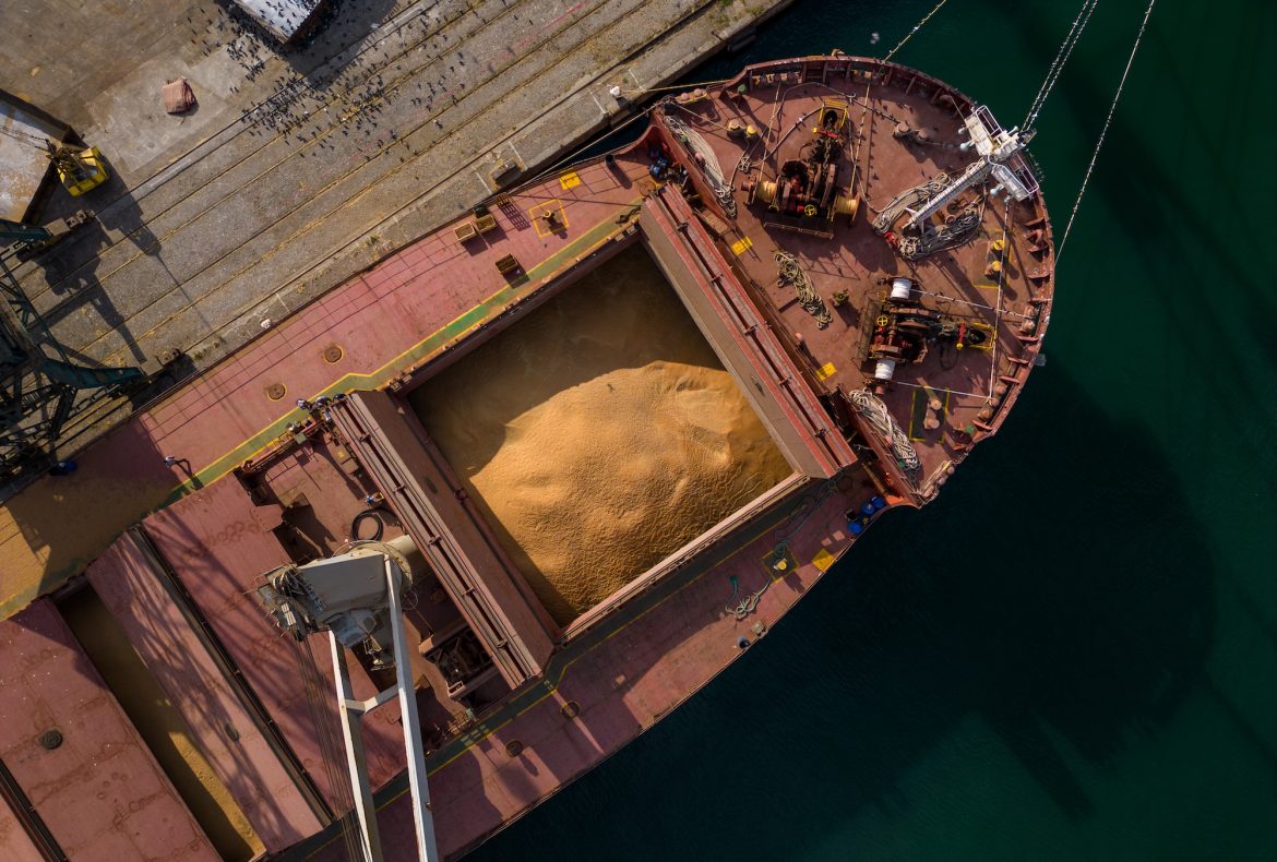 cargo ship or bulk carrier loaded to the brim with grain is preparing for departure, working sailors on deck are completing work, aerial view
